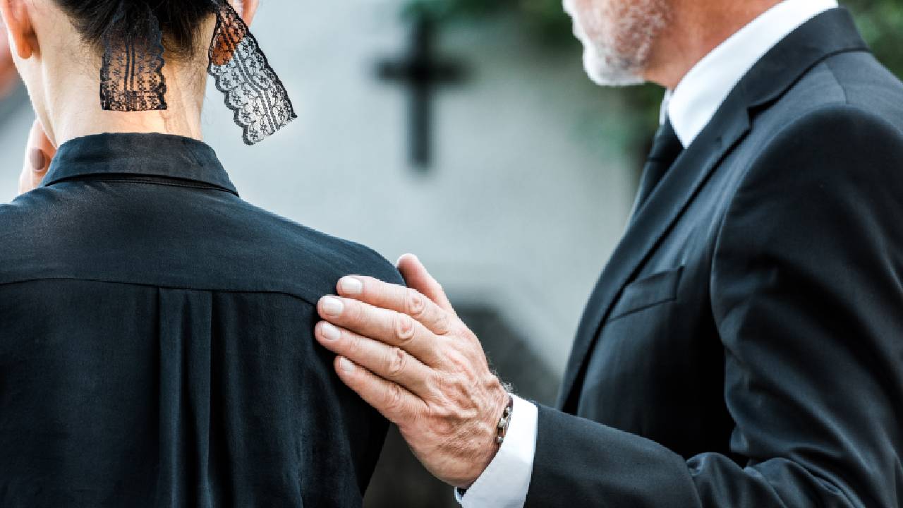 Man holding woman on the shoulder during funeral